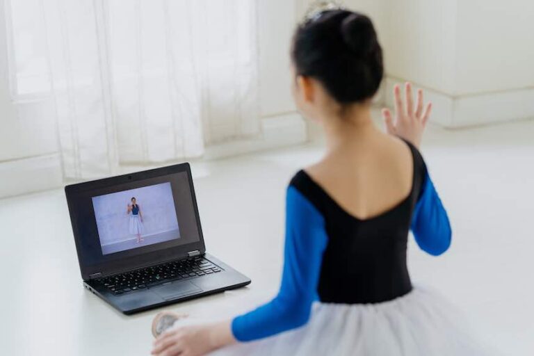Image of a young asian ballerina using laptop and having online ballet lesson with her ballet teacher