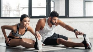What exactly is hyperbolic Stretching? An athletic young man and lady stretching in the gym
